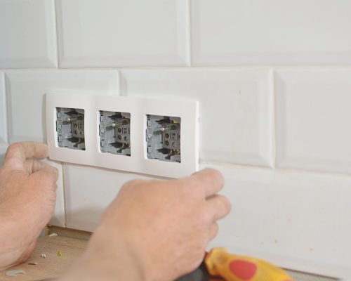 Electrician installing wall socket in new building